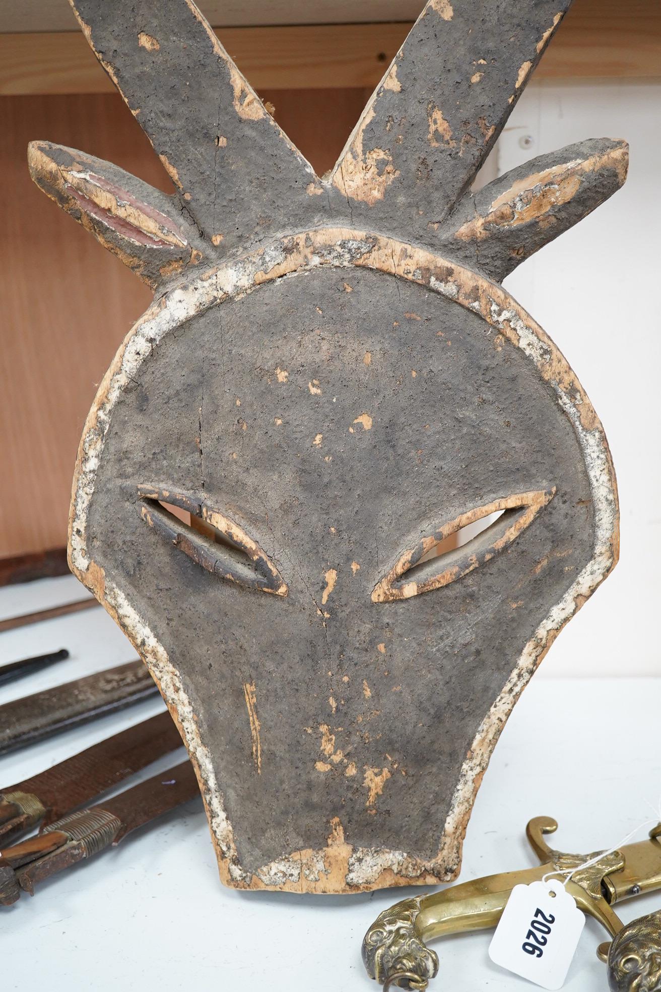 A Kwele painted wood mask in the form of an antelope’s head, 68cm high. Condition - fair, some paint loss.